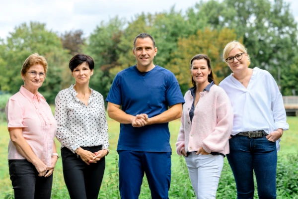 Fünf Erwachsene - vier Frauen und ein Mann - lächeln im Grünen, möglicherweise nachdem sie über Hyaluronspritzen im Knie gesprochen haben.